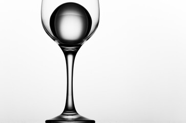 A wine glass with an ice ball. Clear reflections. Separated from background. Minimalistic drinks. Glass ball in a vine glass on white background. Black and white high contrast. 