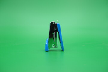 stapler isolated green background. mini stapler upside down upside down.
