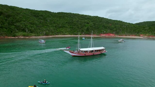 Touristic boat near the Tartaruga beach shoreline  In Brazil, ships gracefully navigate the waters while the lush forest stands tall along the shoreline.