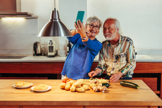 Senior Diverse Couple Taking Selfie While Preparing Dinner Together In Kitchen