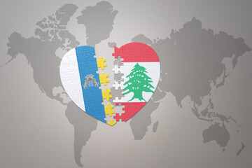 puzzle heart with the national flag of lebanon and canary islands on a world map background.Concept.