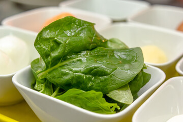 Fresh spinach leaves on dark boel on black background. Healthy vegan food.