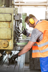 Worker in protective workwear operating machinery in factory