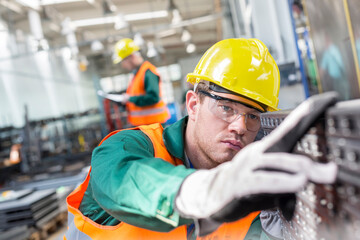 Focused worker examining steel part in factory