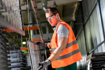 Focused worker holding steel part in factory