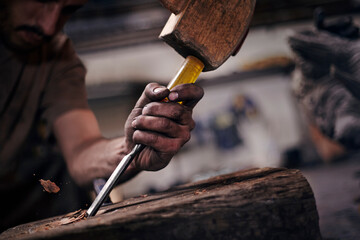 Close up of blacksmith chiseling wood with tool