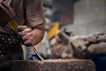 Blacksmith chiseling wood in workshop