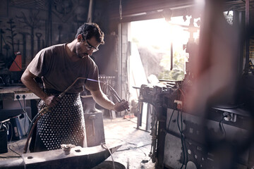 Blacksmith using blow torch in forge