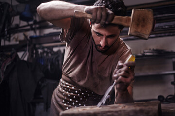 Obraz premium Blacksmith chiseling wood in forge