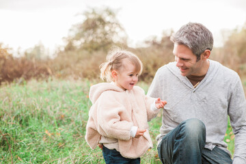 Father and toddler daughter in autumn park