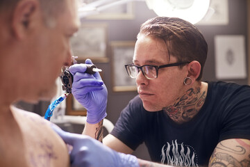 Focused tattoo artist preparing tattoo gun