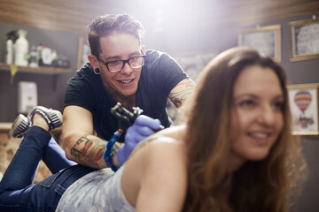 Tattoo artist tattooing woman‚Äôs back