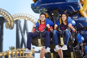 Young couple riding amusement park ride