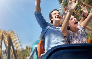 Enthusiastic couple cheering and riding amusement park ride