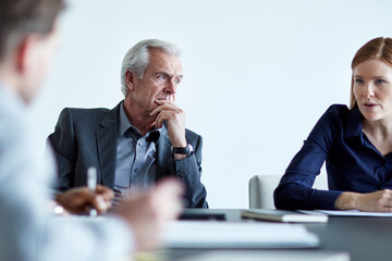 Attentive senior businessman listening to businesswoman in meeting