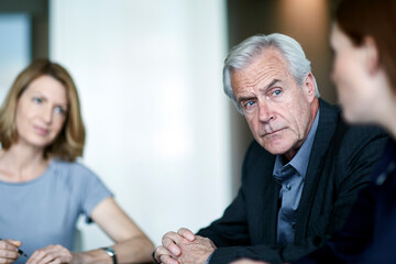 Serious senior businessman listening to businesswoman in meeting