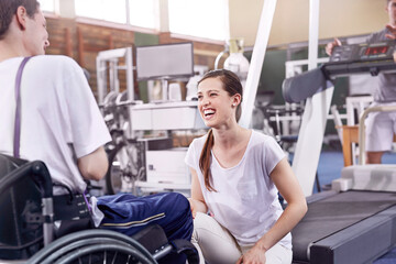 Fototapeta na wymiar Smiling physical therapist talking to man in wheelchair