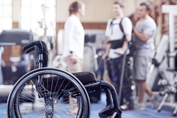 Man receiving physical therapy with wheelchair in foreground - obrazy, fototapety, plakaty
