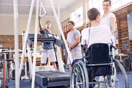 Physical therapists preparing treadmill for man in wheelchair