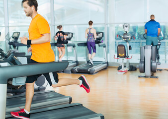 Fototapeta na wymiar Man running on treadmill at gym