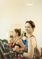 Portrait smiling woman jogging on treadmill at gym