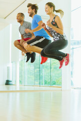 Enthusiastic men and woman jumping in exercise class