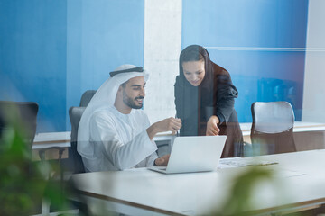 Handsome man and woman with traditional clothes working in an office of Dubai