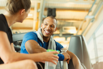 Smiling man and woman talking at gym