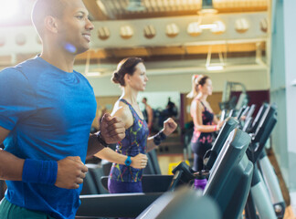 Fototapeta na wymiar Smiling man running on treadmill at gym