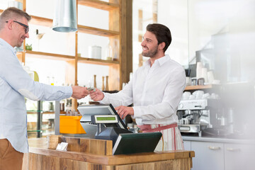 Fototapeta na wymiar Customer paying worker at cafe cash register