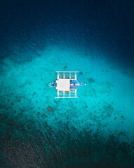 Diving bangka boat in the Phillipines surrounded by crystal clear blue water and coral reef, view from a drone in Coron, Palawan Island