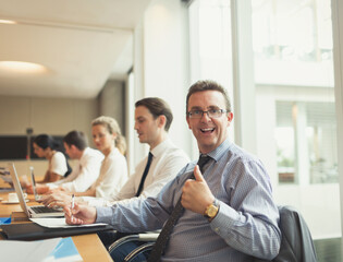 Portrait confident businessman gesturing thumbs-up in conference room meeting