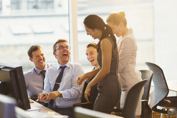 Laughing business people at computer in office
