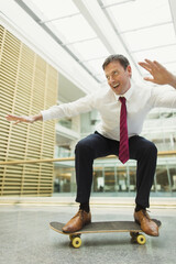 Playful businessman skateboarding in office