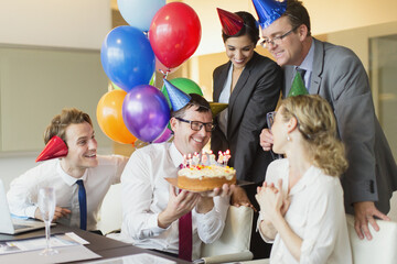 Colleagues presenting businesswoman birthday cake in conference room