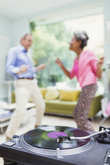 Playful nature couple dancing in living room behind record player