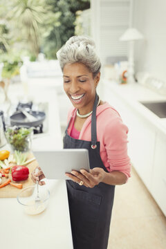 Smiling Mature Woman With Digital Tablet Cooking In Kitchen