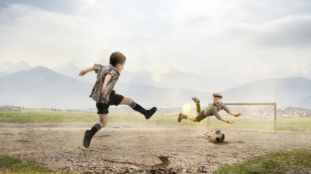 Dynamic image. Winning goal. Two little boys, children in retro style clothes playing football outdoors on a daytime