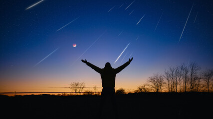 Silhouette of a man with Milky Way starry skies, Moon eclipse and meteor shower. © astrosystem