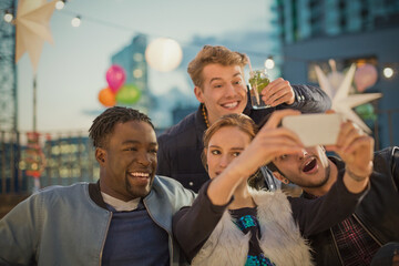 Young adult friends taking selfie at rooftop party