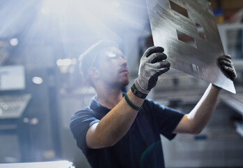 Worker examining piece in steel factory - obrazy, fototapety, plakaty