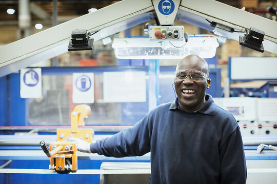 Portrait smiling worker at machine in steel factory