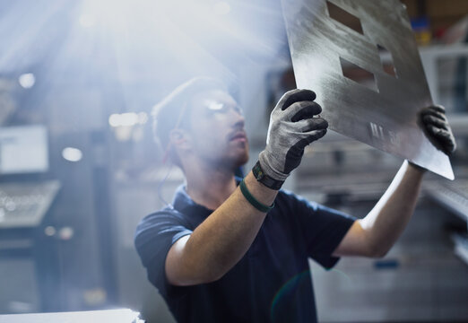 Worker examining piece in steel factory