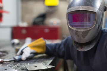 Portrait of welder in welding helmet in steel factory - obrazy, fototapety, plakaty
