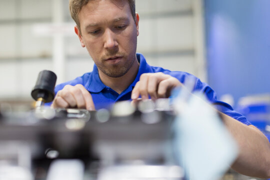 Worker examining machinery in steel factory - Powered by Adobe