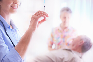 Doctor preparing syringe near senior man