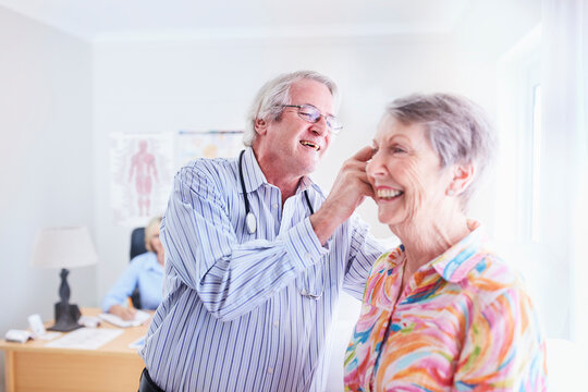 Doctor examining senior woman‚Äôs ear in checkup