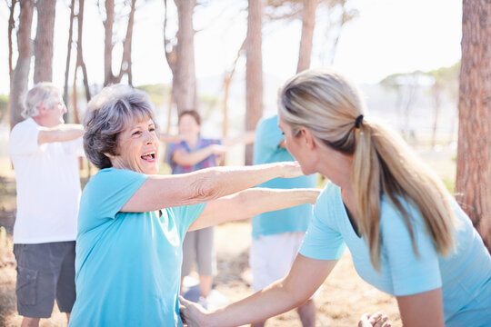 Yoga instructor guiding senior woman in park