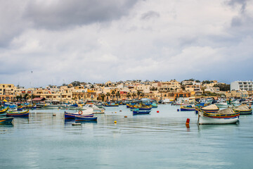 Fototapeta na wymiar Boats mooring outside waterfront town, Marsaxlokk, Malta