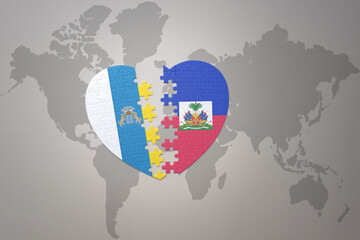 puzzle heart with the national flag of haiti and canary islands on a world map background.Concept.